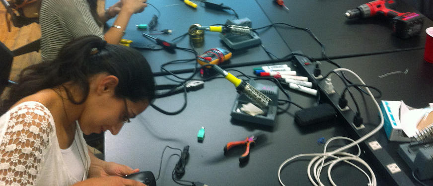 a group of occupational therapists at a table learning to solder during a workshop.