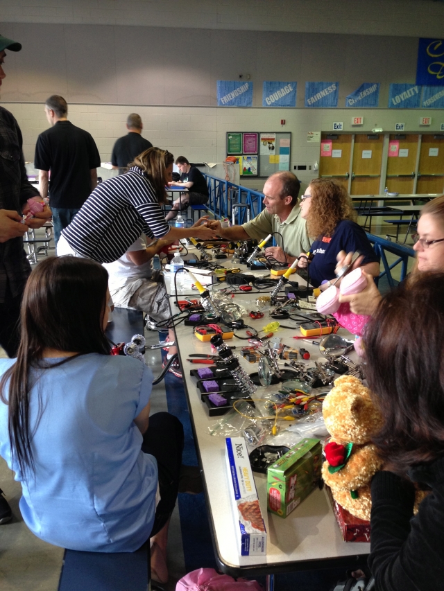 people working at a table with soldering irons and hacking toys